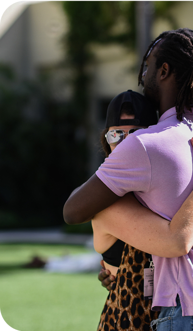 Two attendees hugging on the Hilton West Palm Beach lawn at Eudēmonia Summit 2024